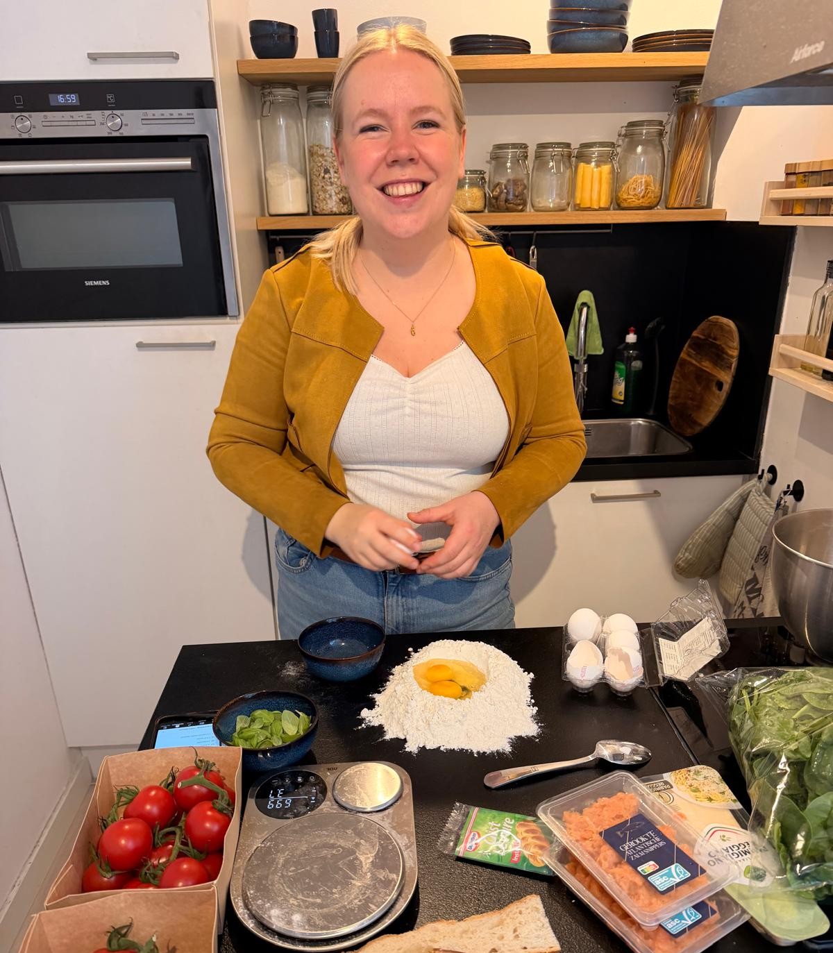 Aniek lacht in haar keuken achter een berg bloem met eieren, klaar om pastadeeg te maken